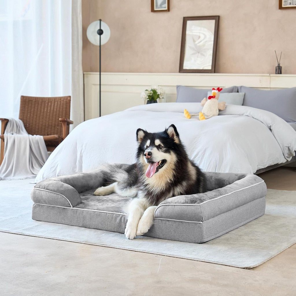 Gray dog bed with removable cover and cushioned sides, with a lying black and white dog