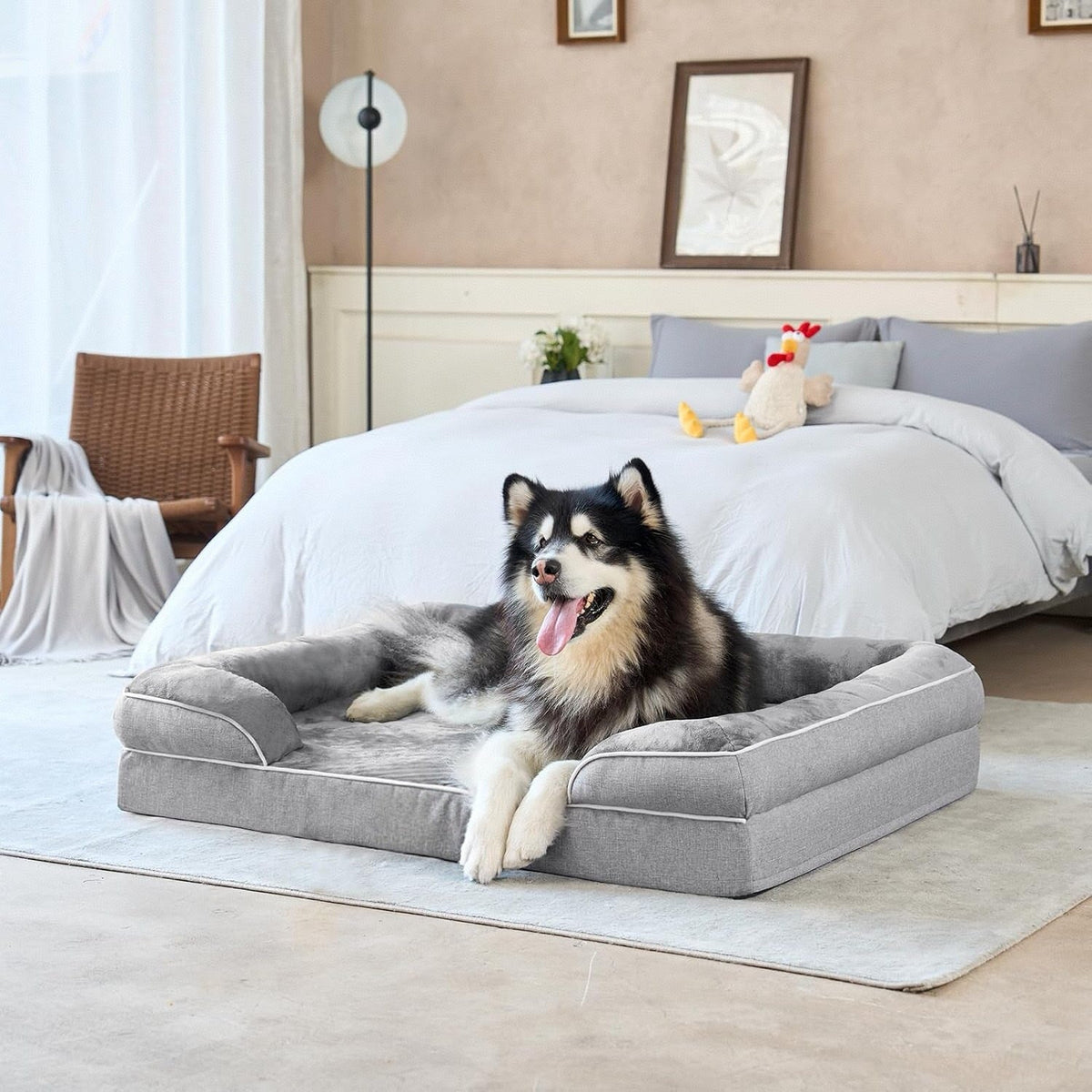 Gray dog bed with removable cover and cushioned sides, with a lying black and white dog