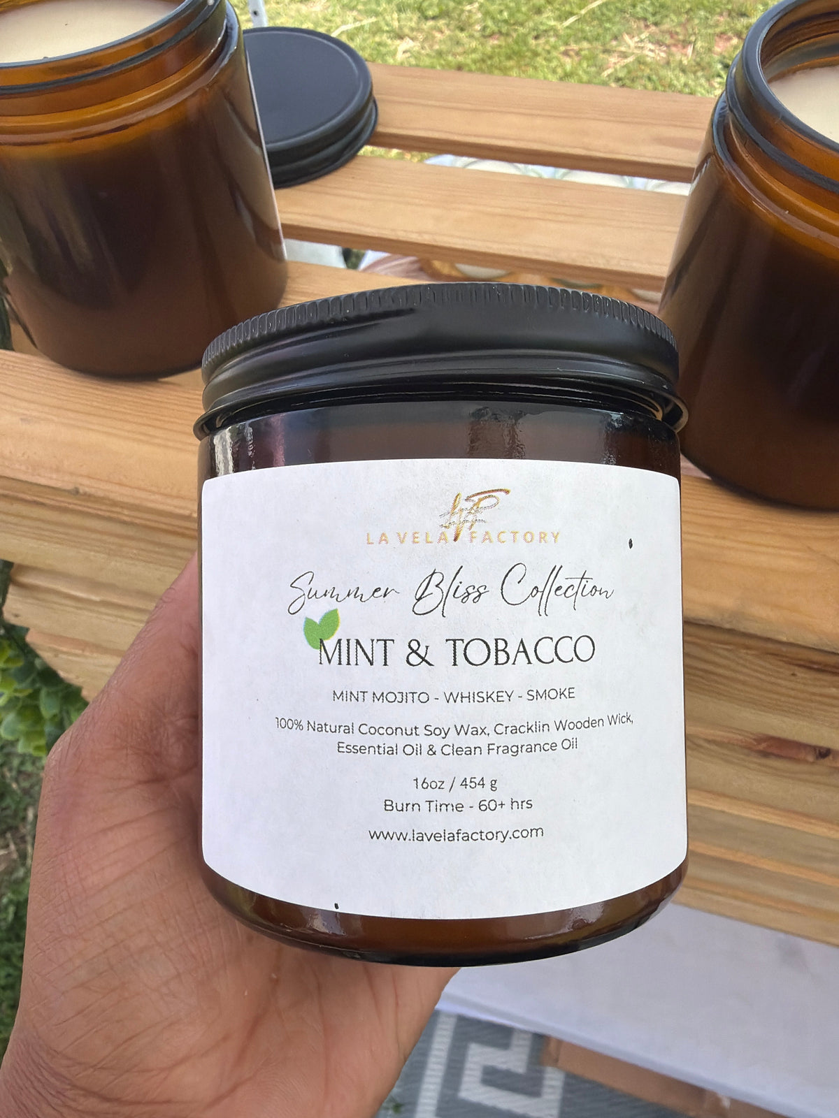Amber glass jar candle with black lid, label for “Mint & Tobacco”