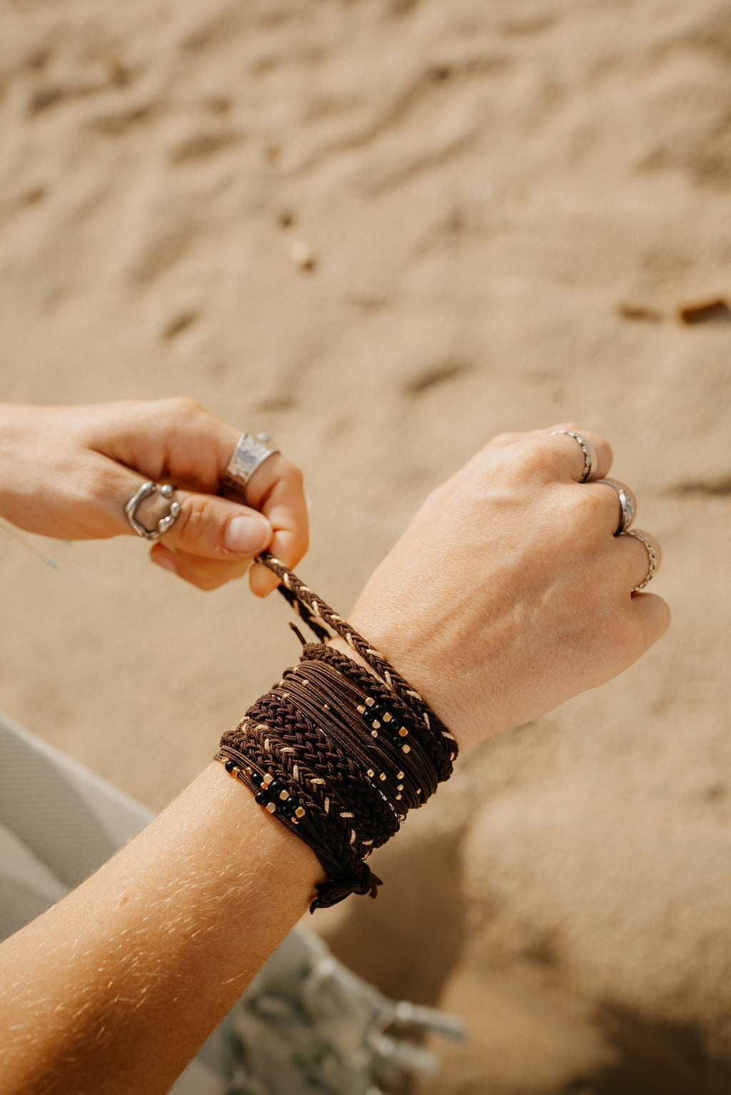 Mocha-toned braided hair tie bracelets stacked on the wrist