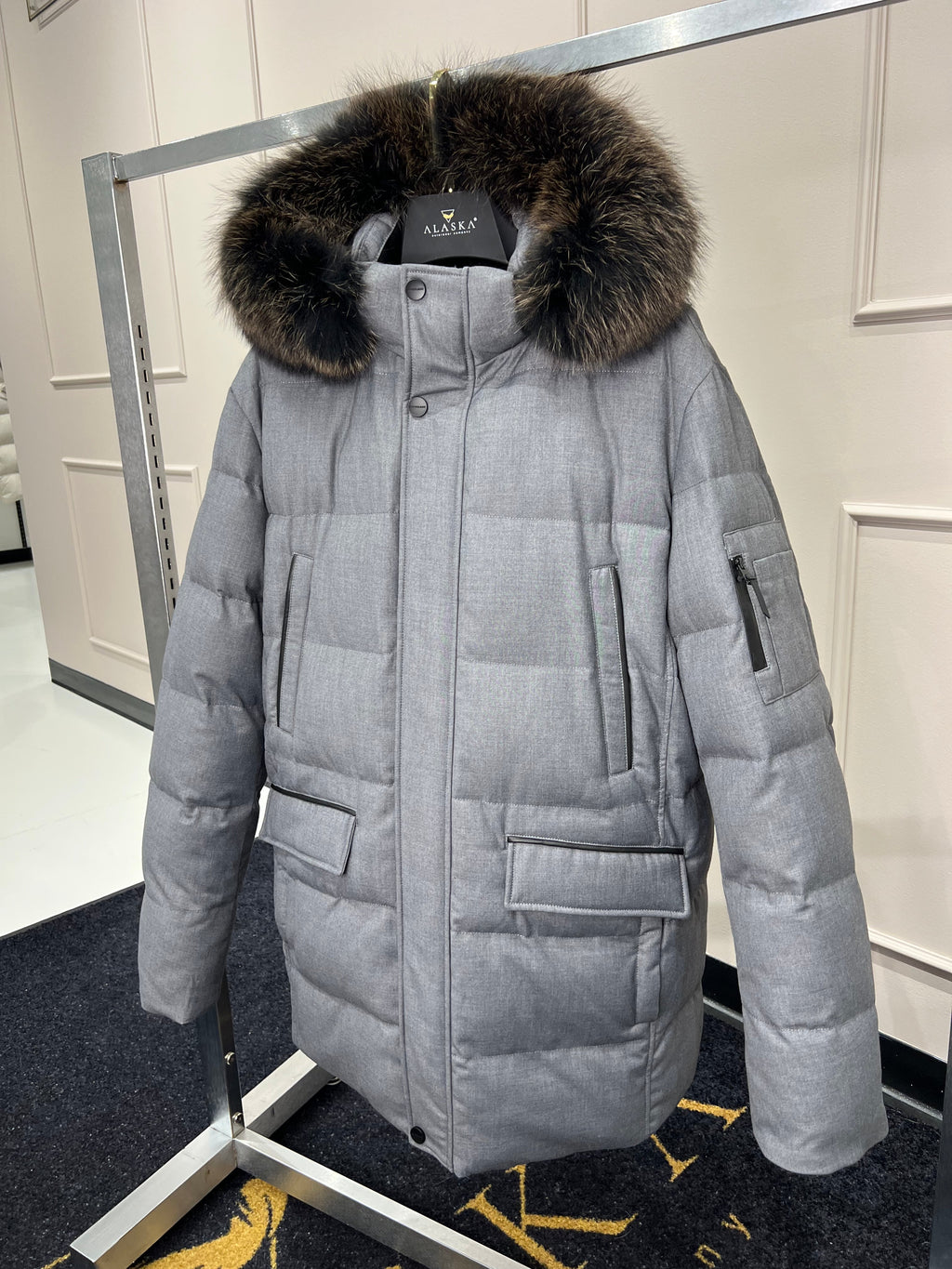 Grey long puffer coat with faux fur hood trim, front zipper, and side pockets
