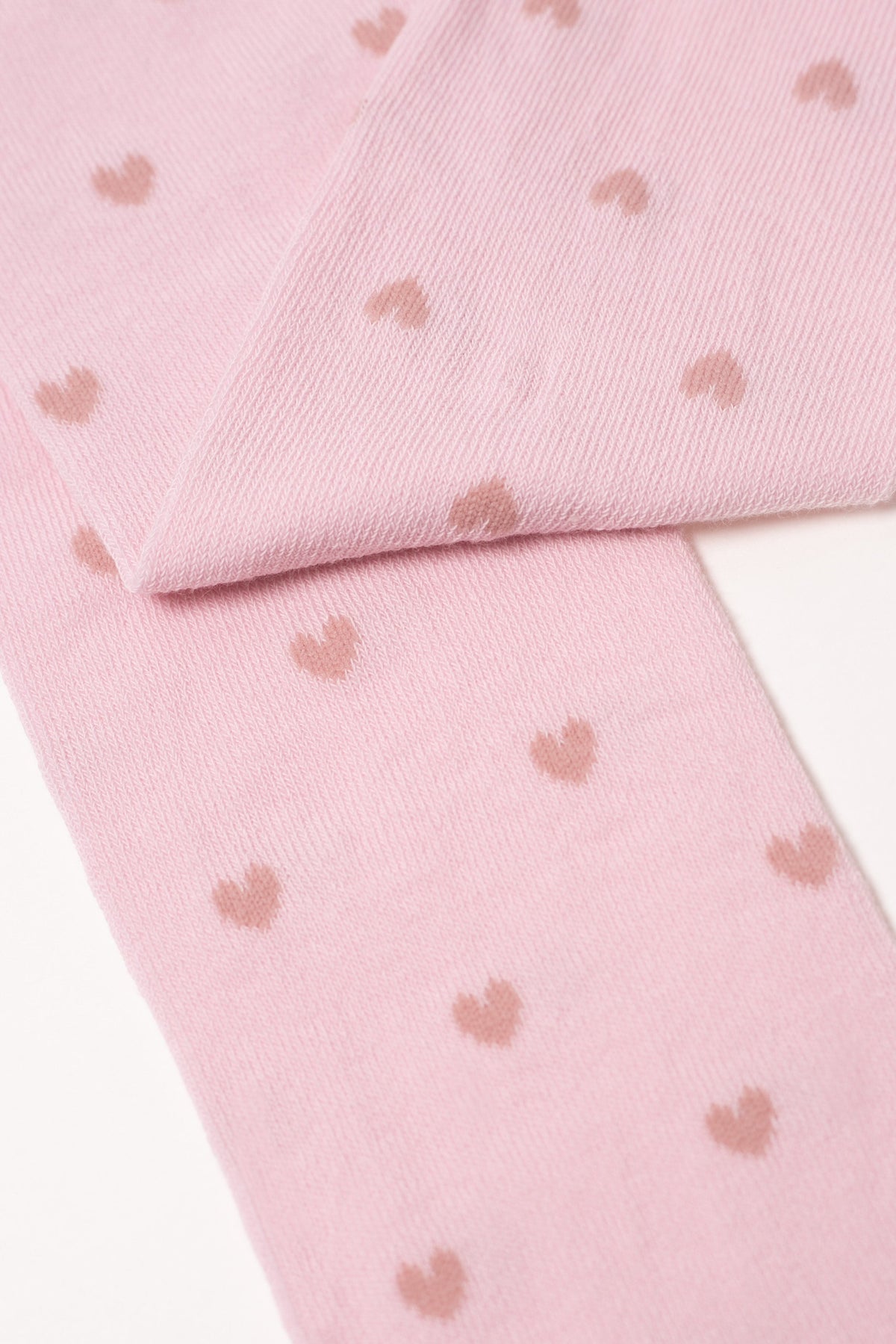 Light pink kids cotton tights with small brown hearts, folded fabric close-up