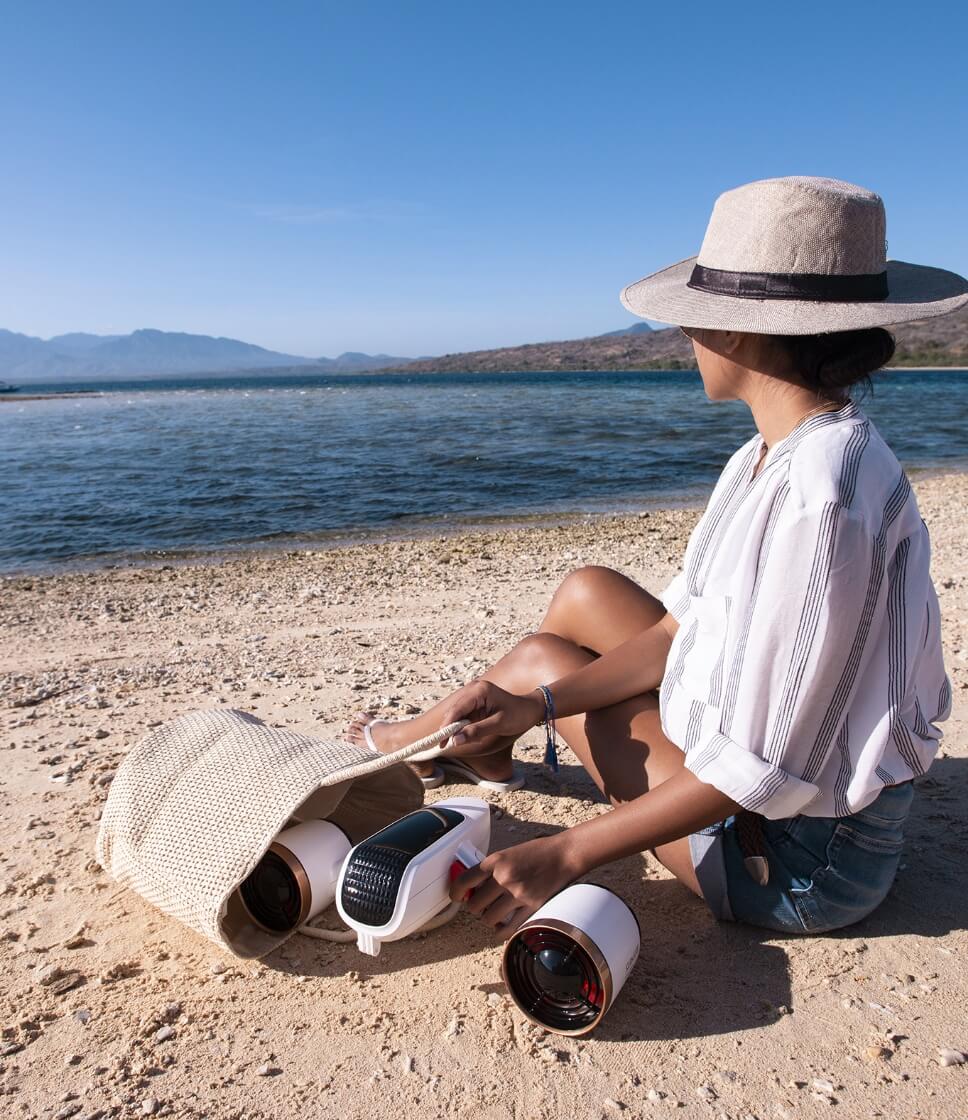Handheld underwater camera with rounded housing, held on sandy beach