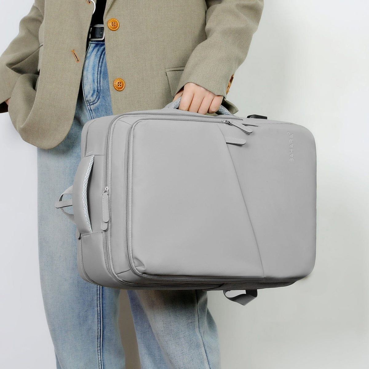 Storm gray travel backpack carried by person with front zipper pocket