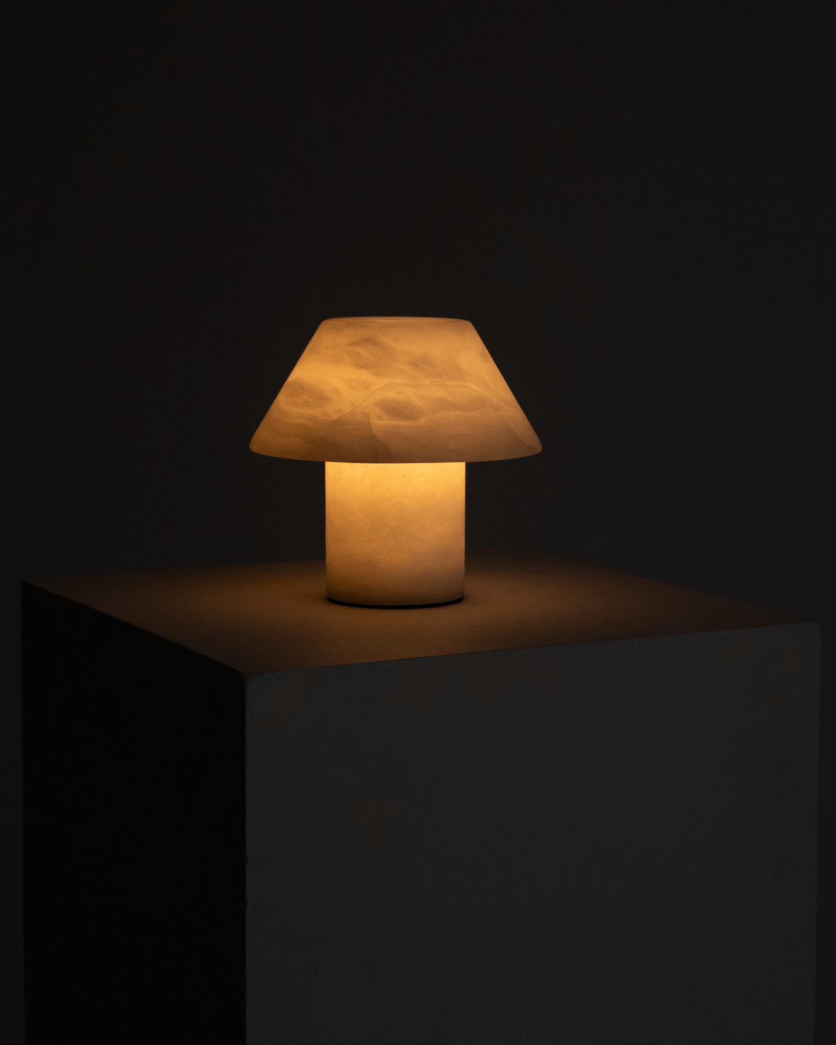 Warm-toned table lamp with fabric cone shade and cylindrical base, lit
