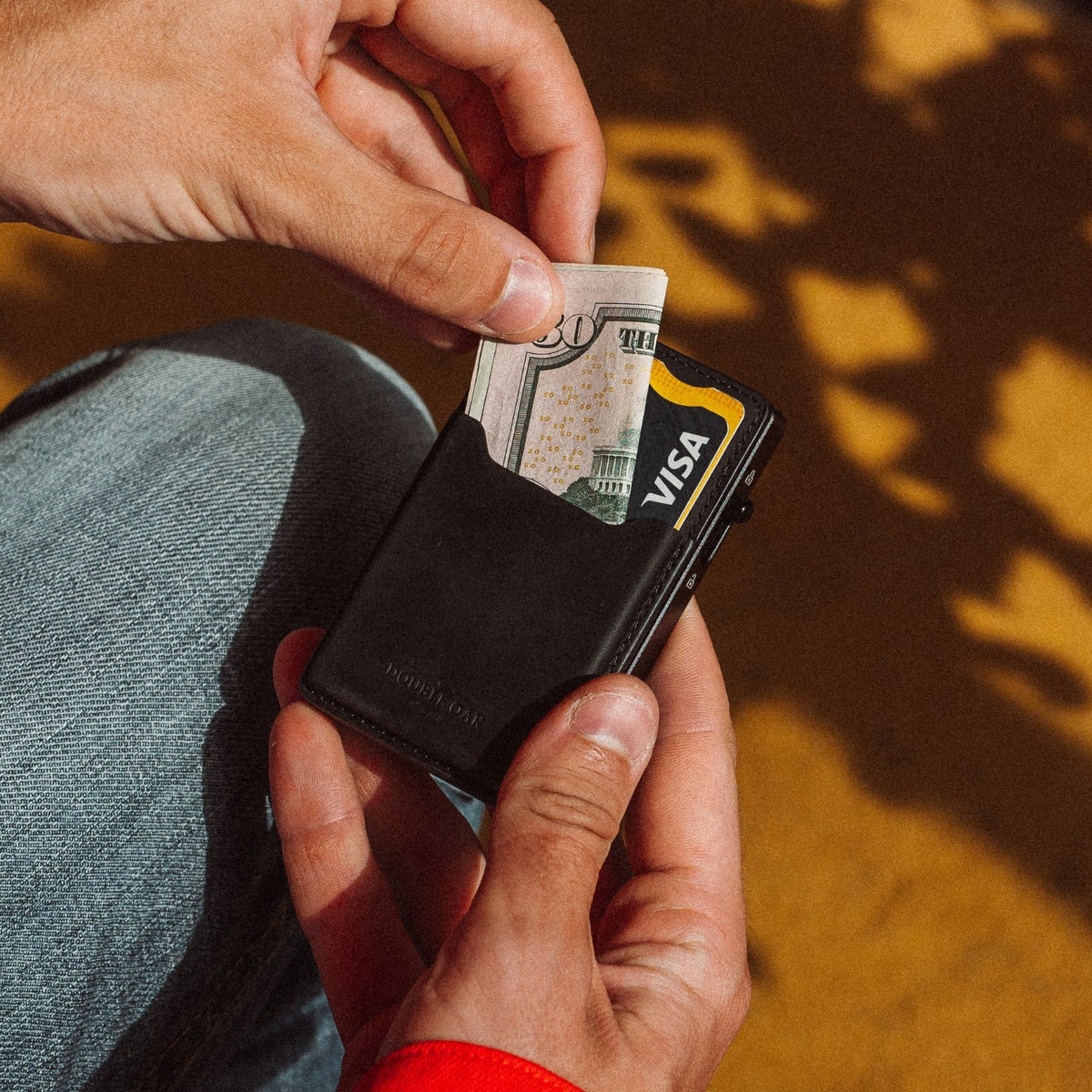 Black leather cardholder wallet with cards partly pulled, yellow trim visible.