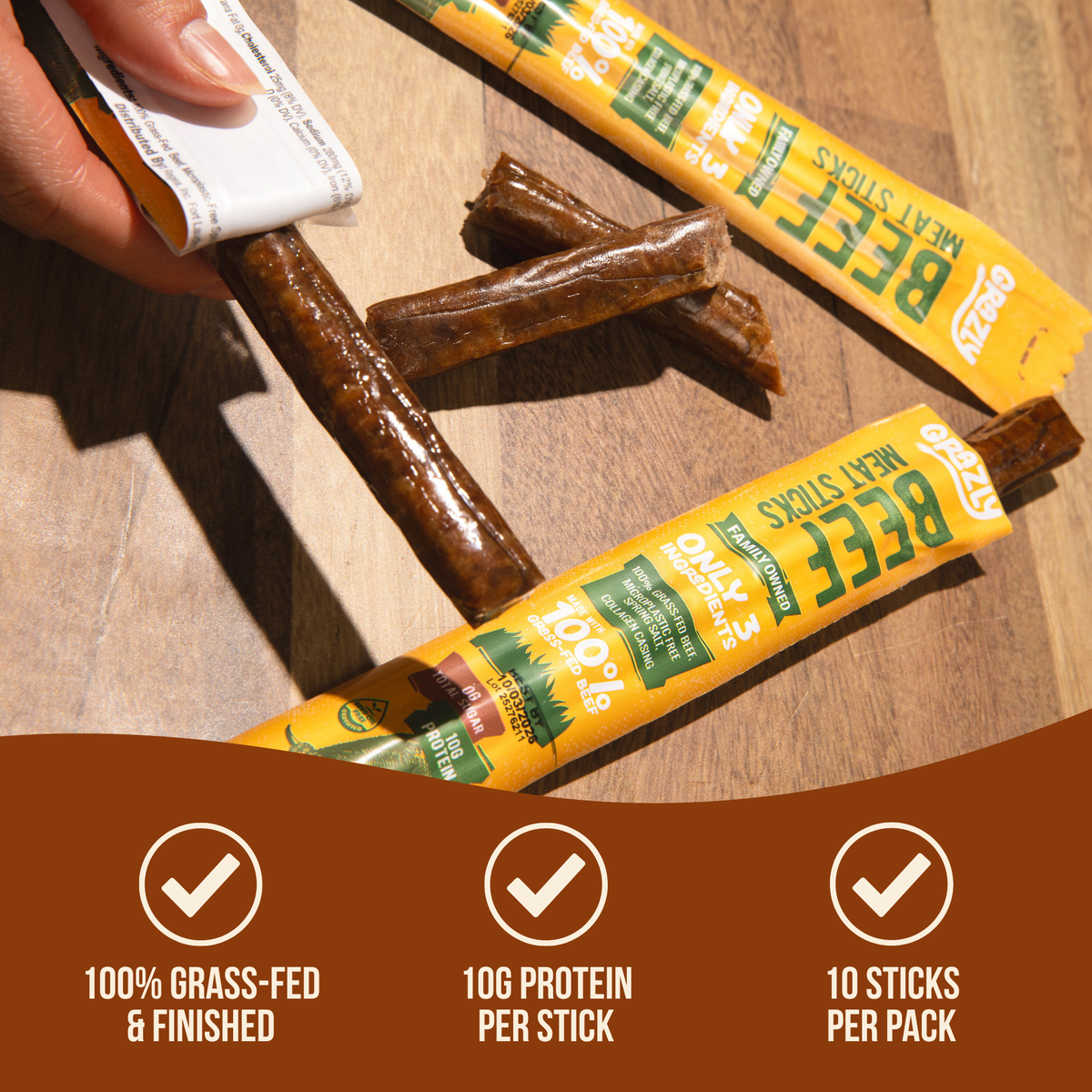 Beef meat sticks and opened yellow packages on a wooden surface