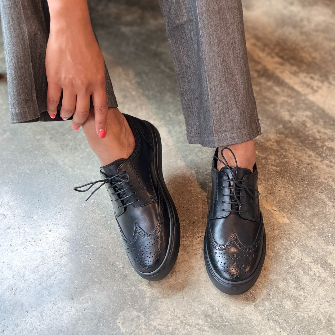 Black lace-up dress shoes with brogue perforations and flat rubber sole