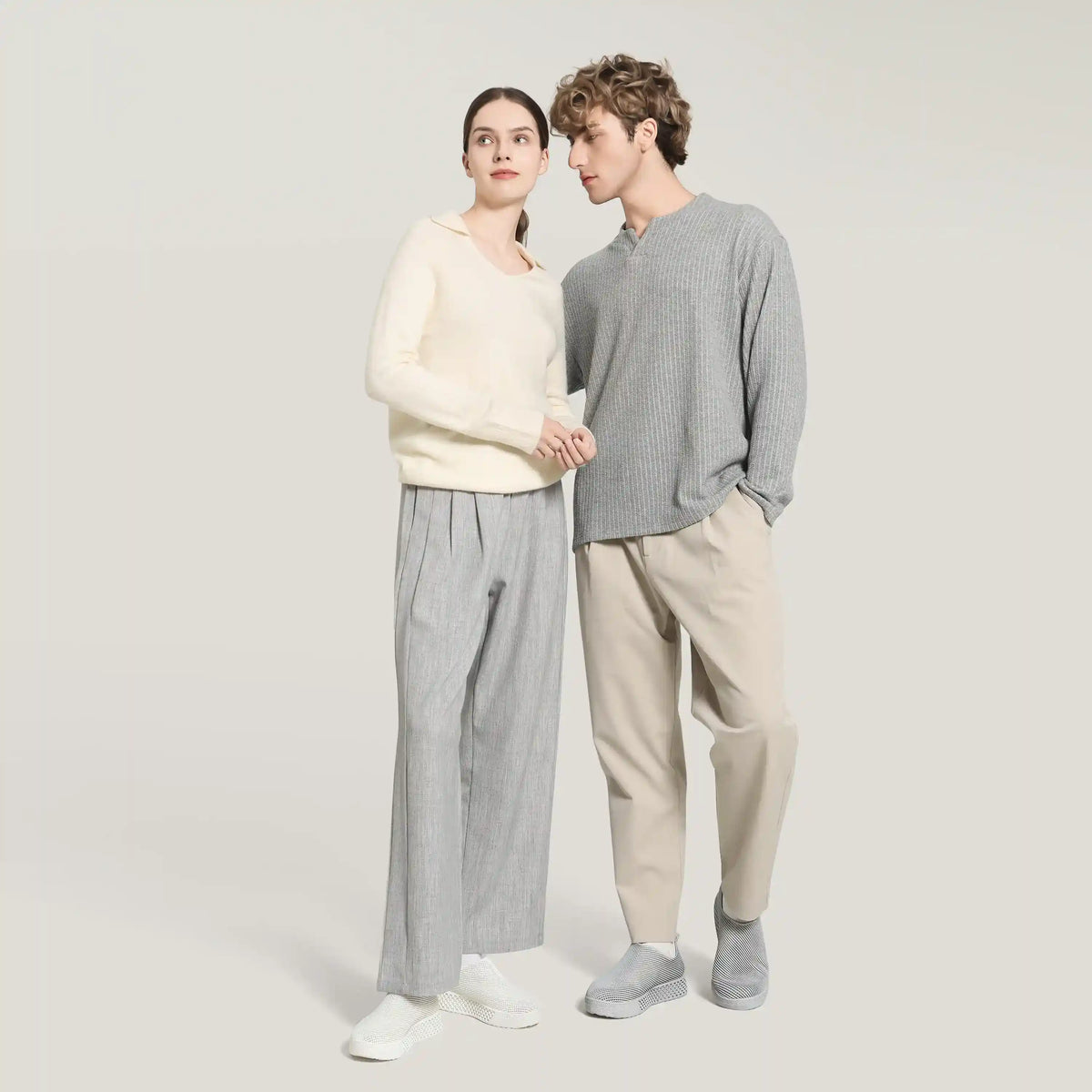 White 3D-printed slip-on sneakers on two models wearing light and gray outfits