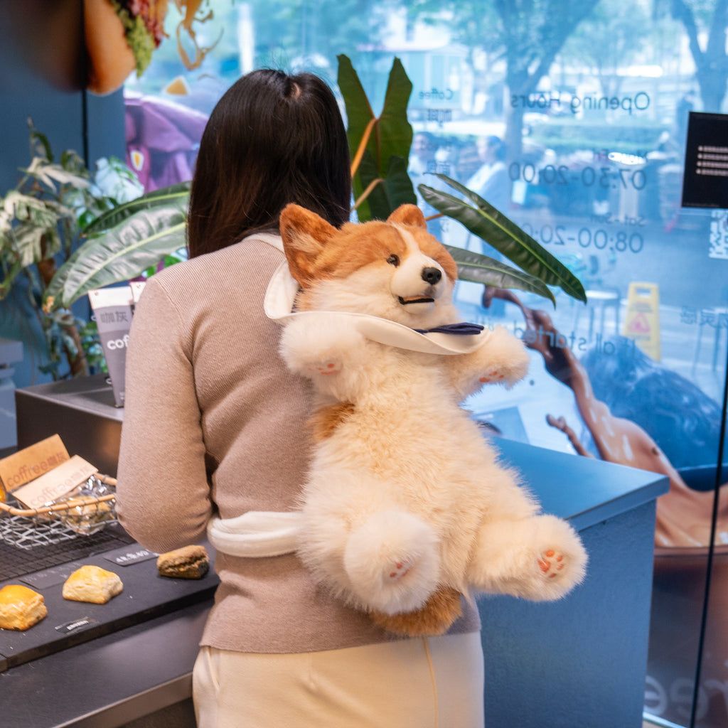Corgi plush backpack being worn, with white fur and navy bow detail
