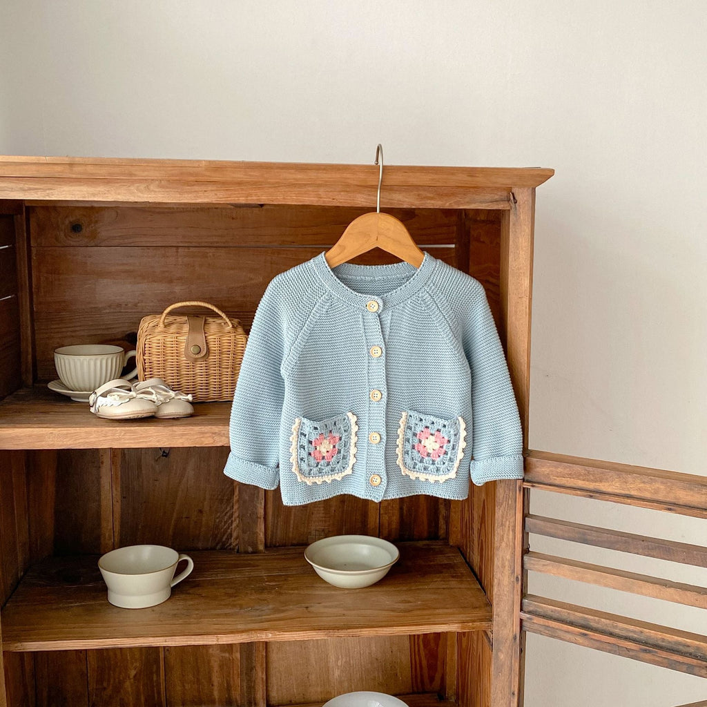 Smokey blue knit cardigan on hanger with round collar, button front, crochet flower pockets