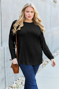 Black relaxed long sleeve crewneck tee with curved hem and side slits