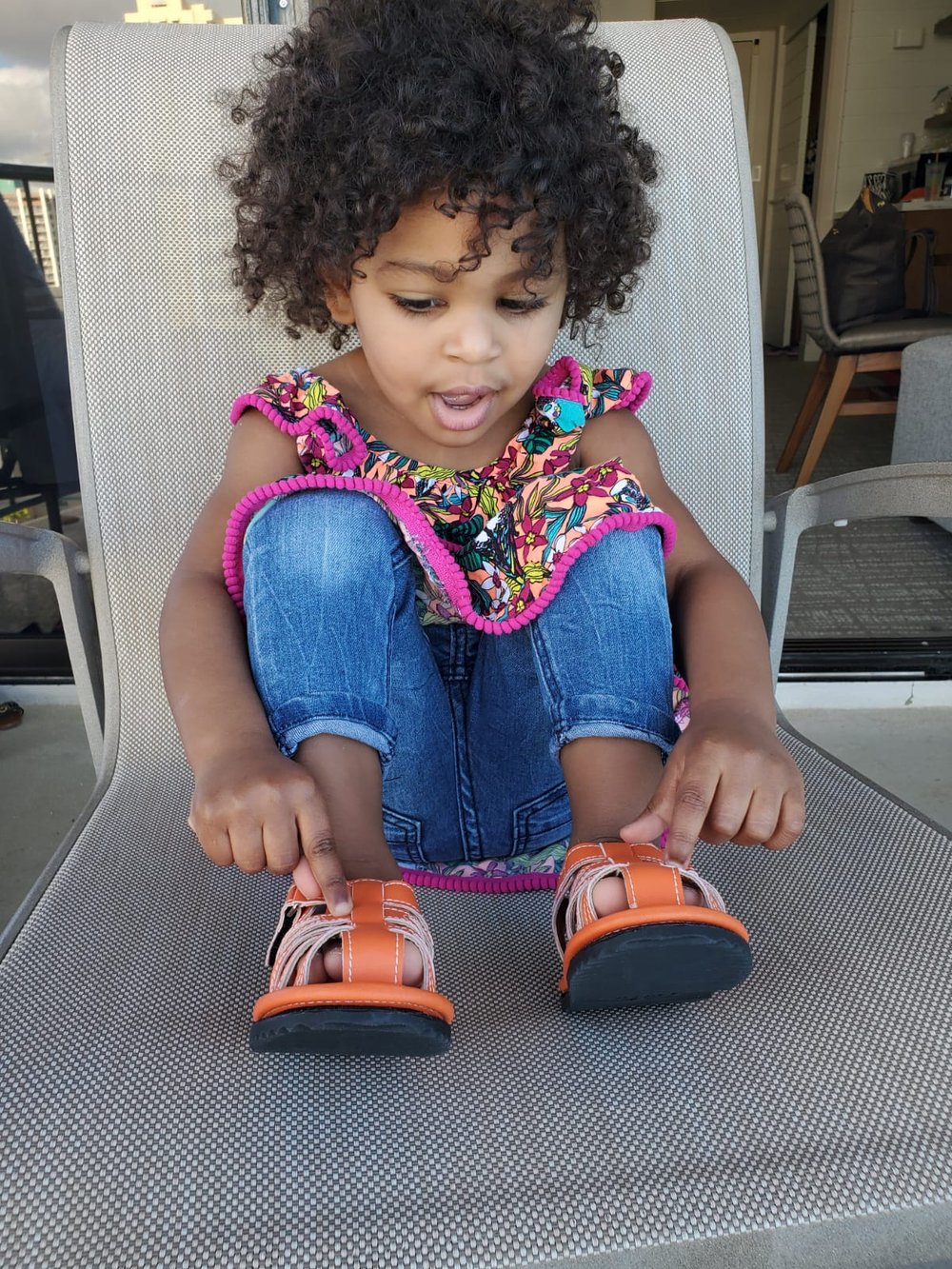 Orange kids sandals worn on a child, open toe with hook-and-loop straps