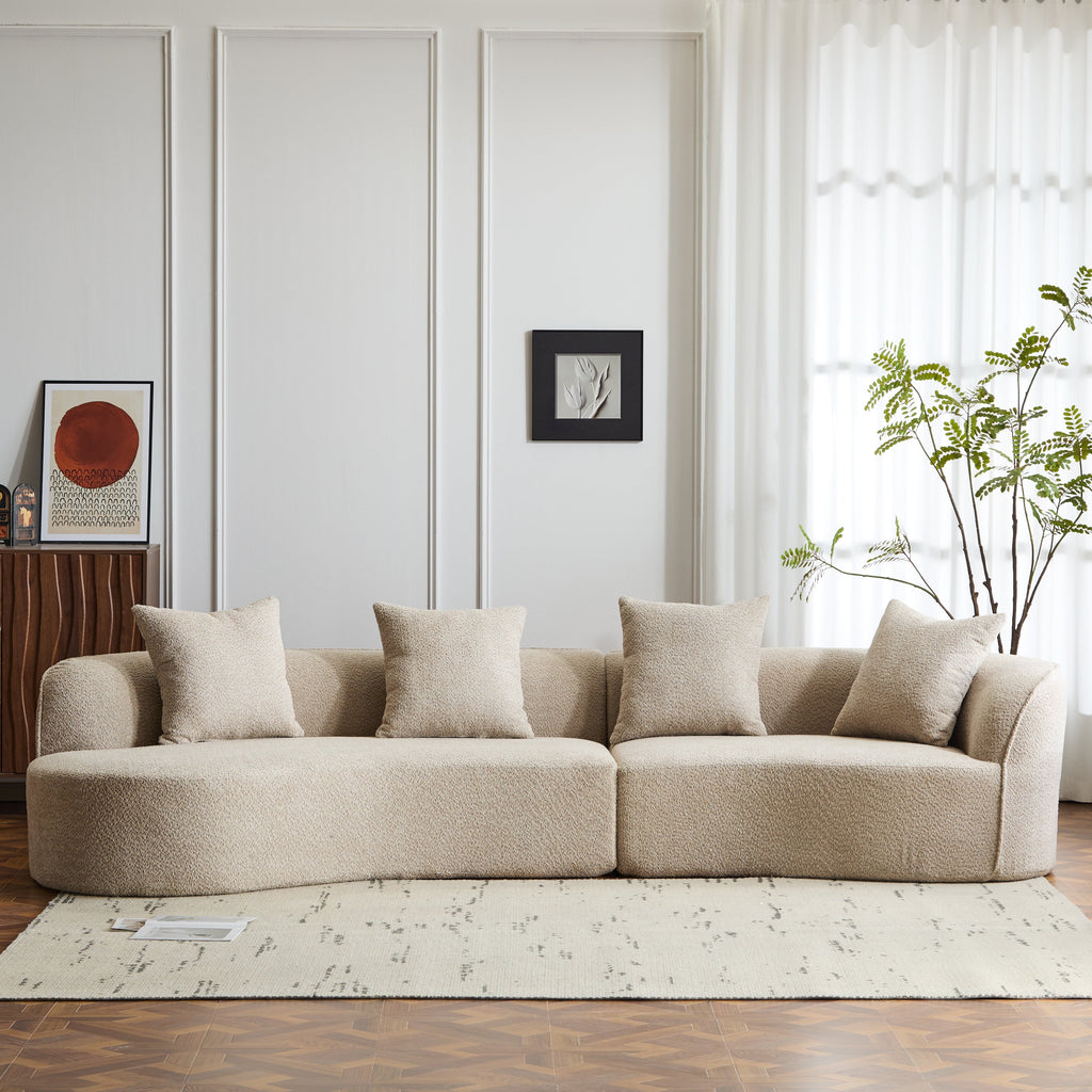 Light beige curved sectional sofa with four throw pillows and padded armrests