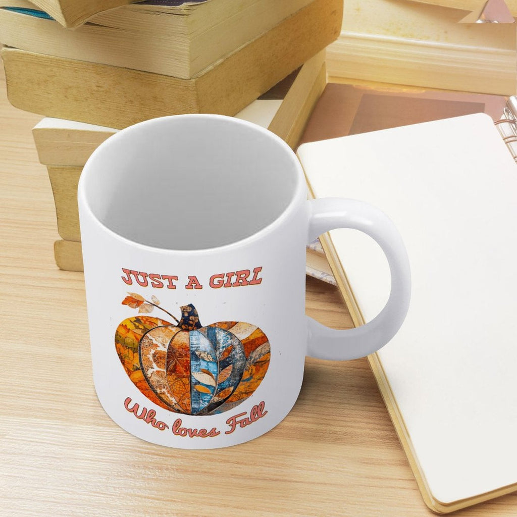 White ceramic mug with handle, pumpkin graphic, standing on a light wood surface