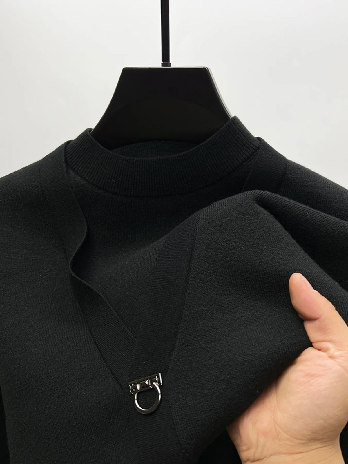 Black knit sweater close-up: ribbed turtleneck collar and ring-loop chest closure