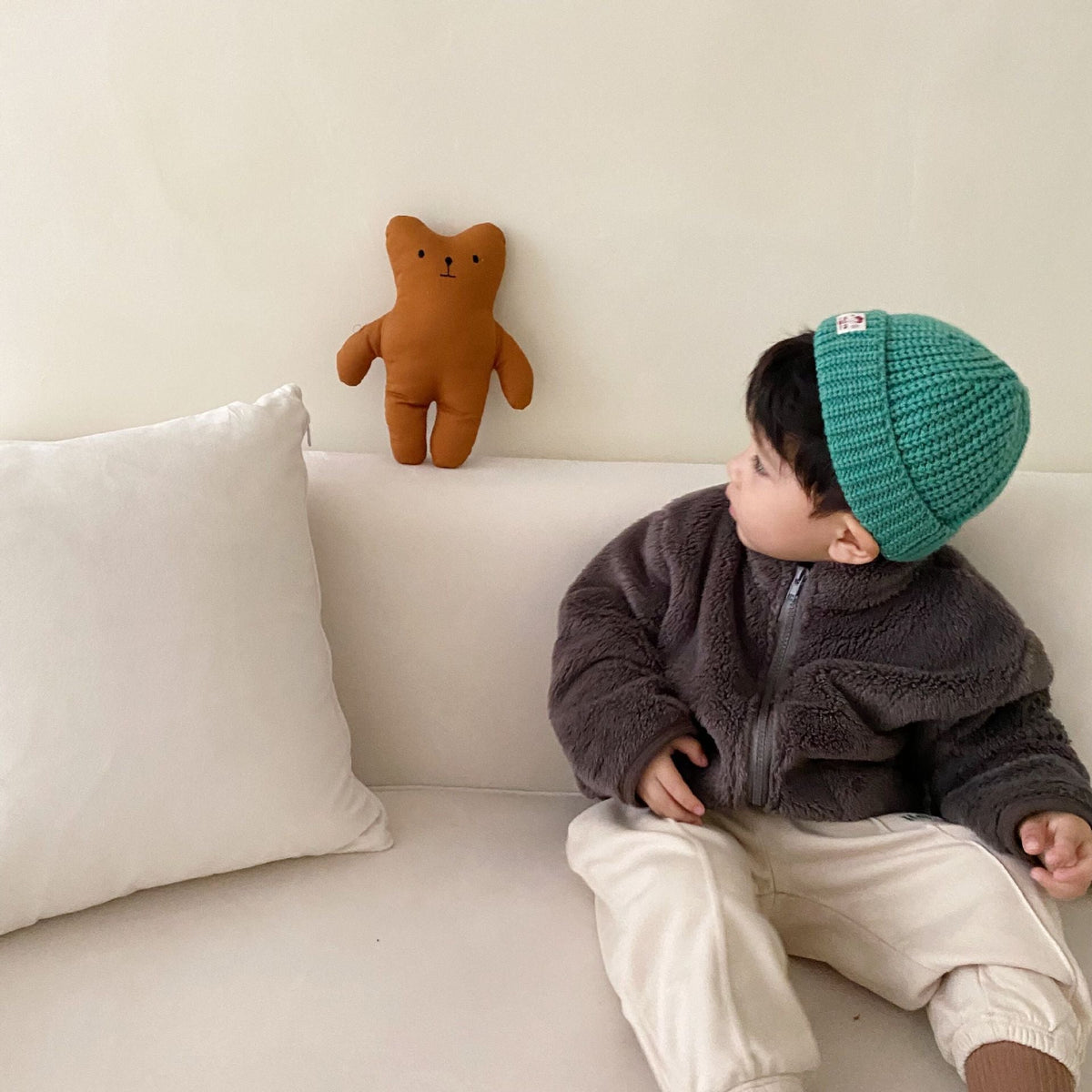 Dark grey kids fleece zip jacket with hood, worn with a green knit beanie.