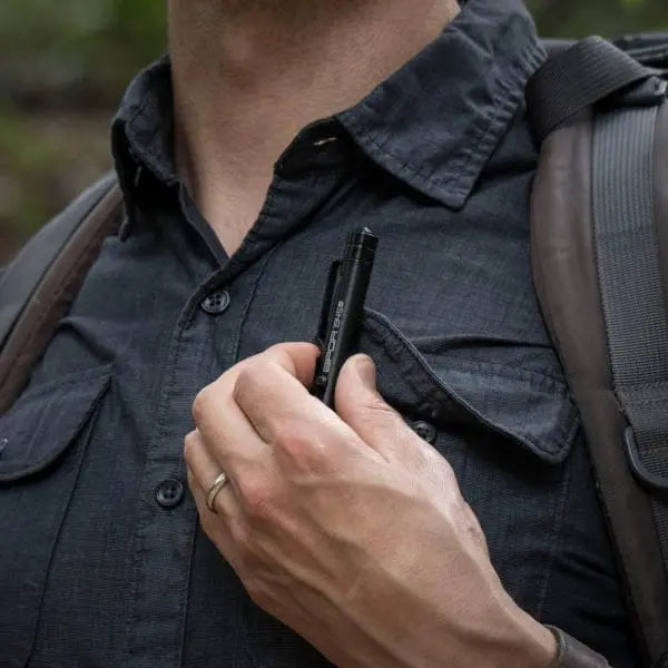 Bolt-action EDC pen in hand near shirt pocket, clip visible
