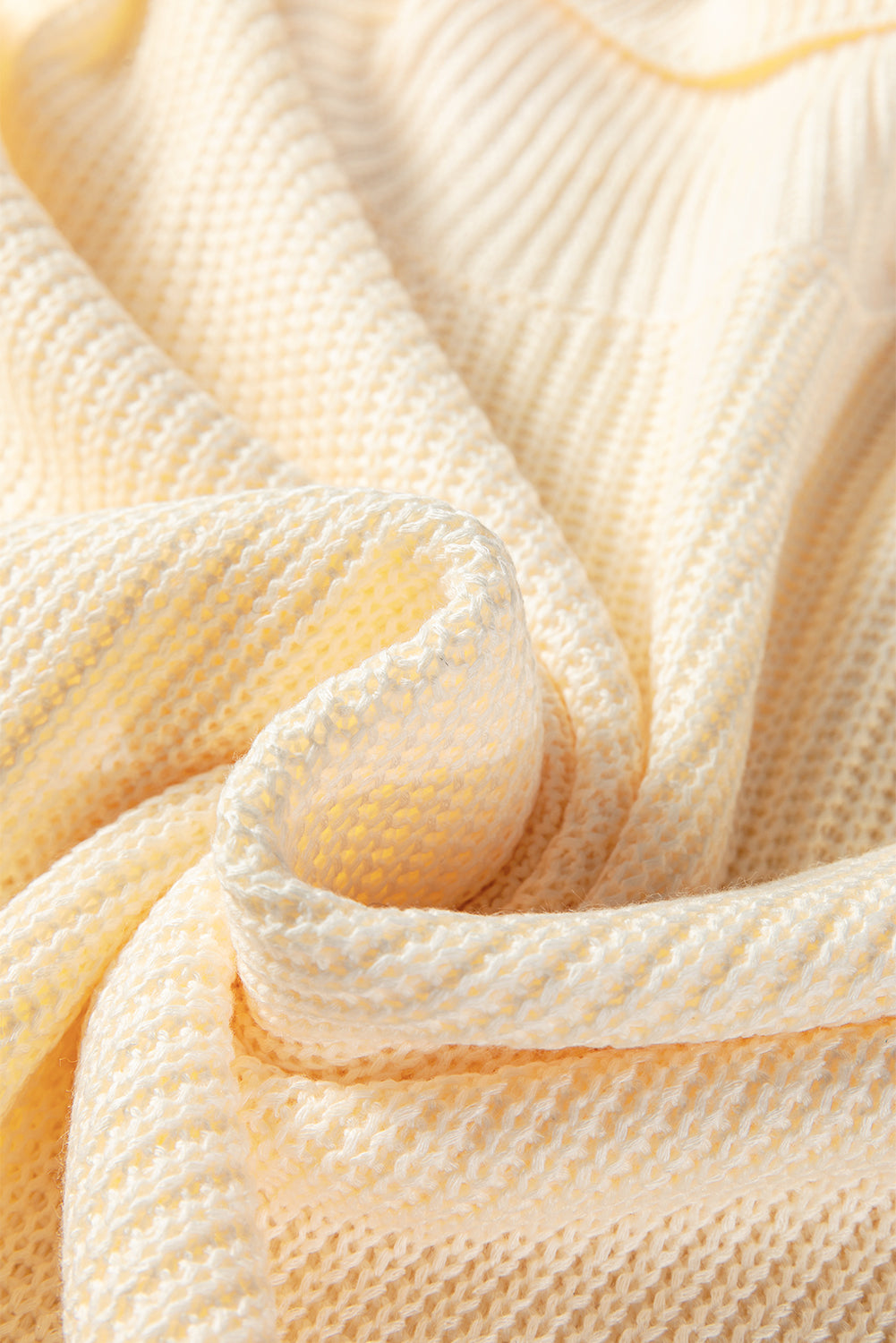 Cream textured knit fabric close-up with ribbed turtleneck edge