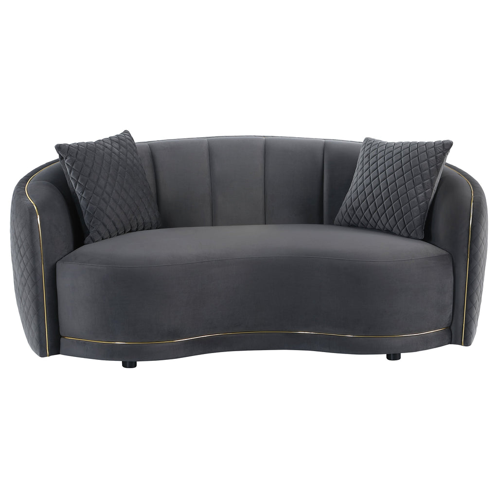 Dark grey velvet two-seat sofa with quilted side panels, two accent pillows, gold trim
