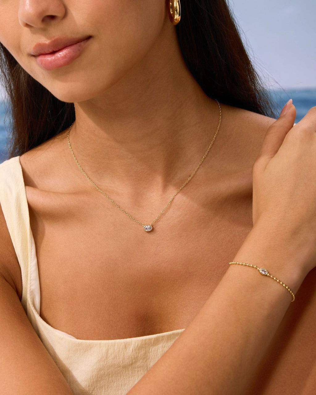 Gold chain necklace with small oval diamond pendant and thin gold bracelet