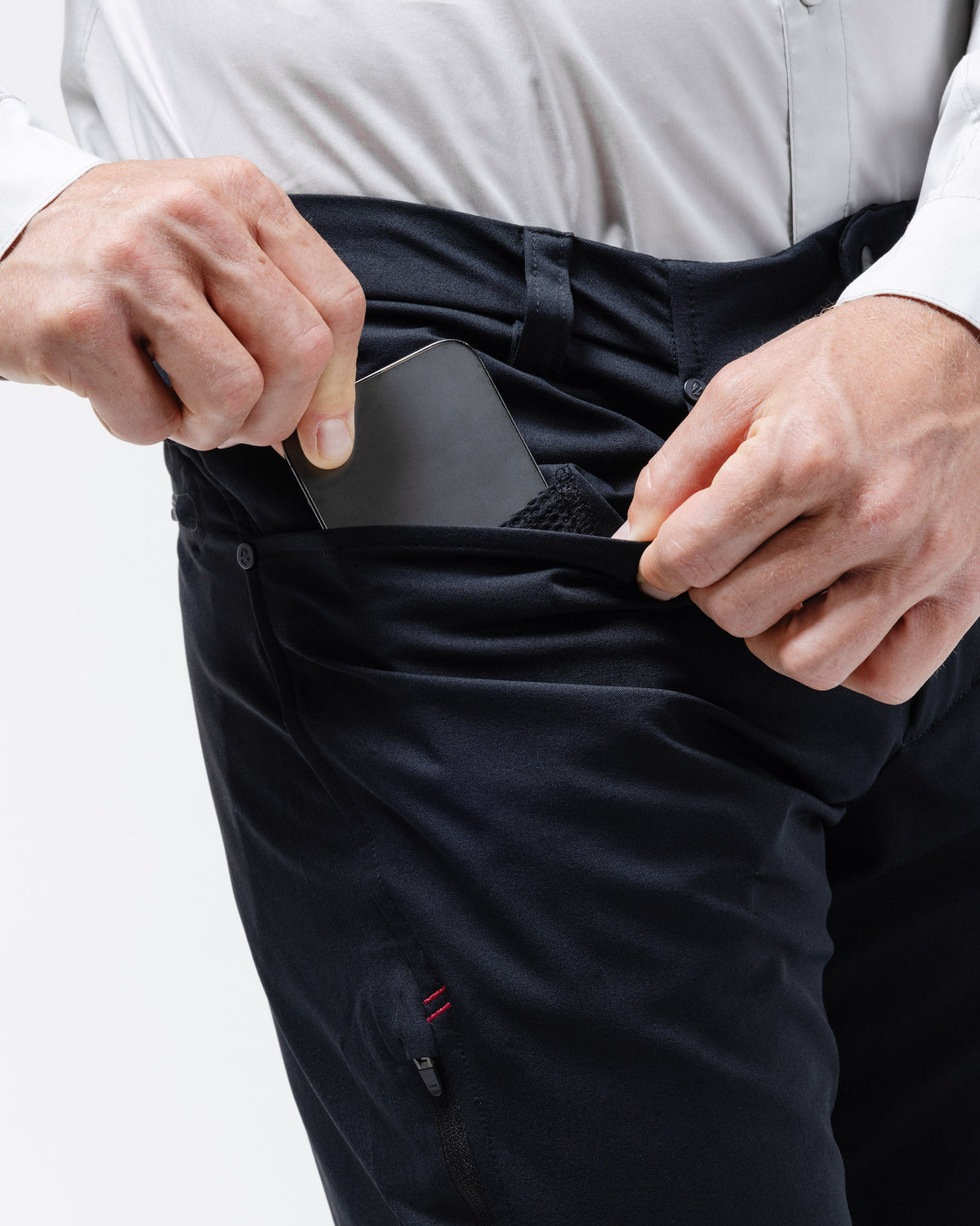 Black chino pants detail of hands adjusting front pockets and fabric texture.