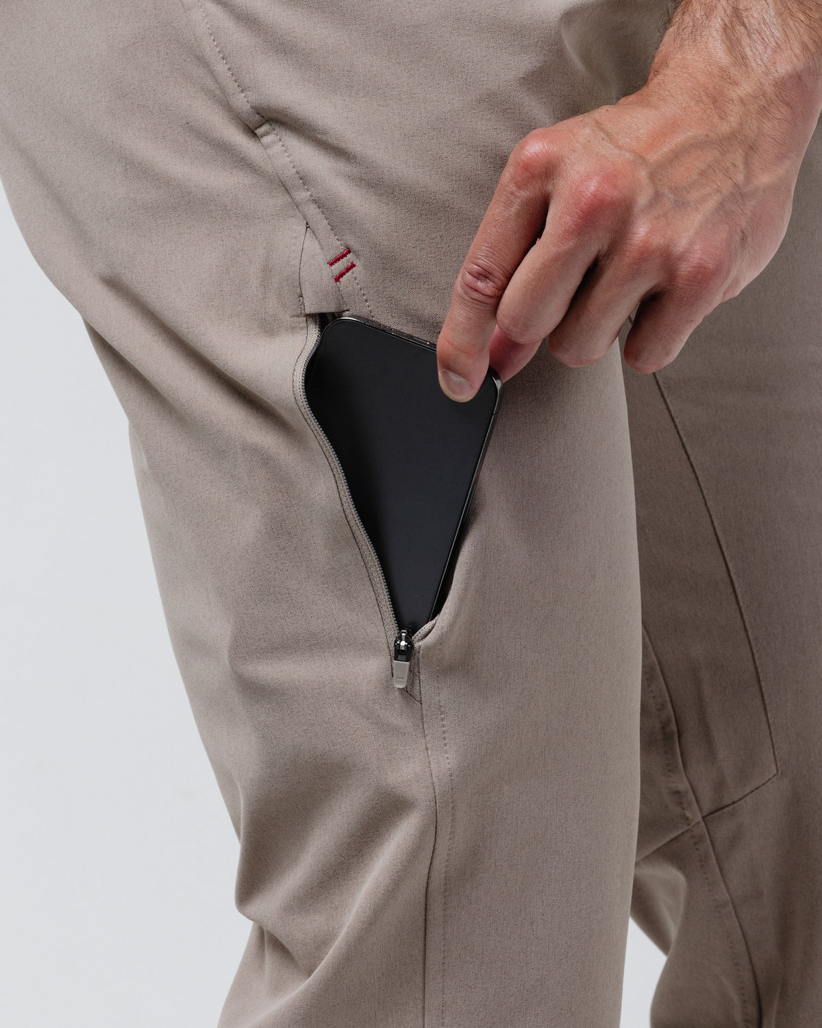 Tan chino pants close-up of zipper coin pocket opening at side