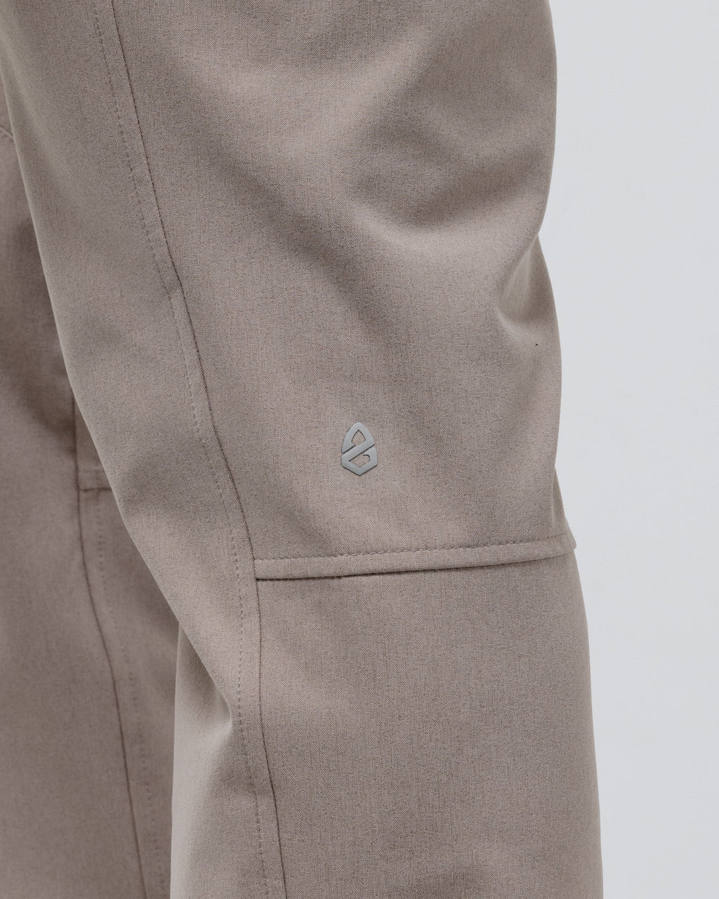 Tan chino pants close-up of small logo patch near cuff