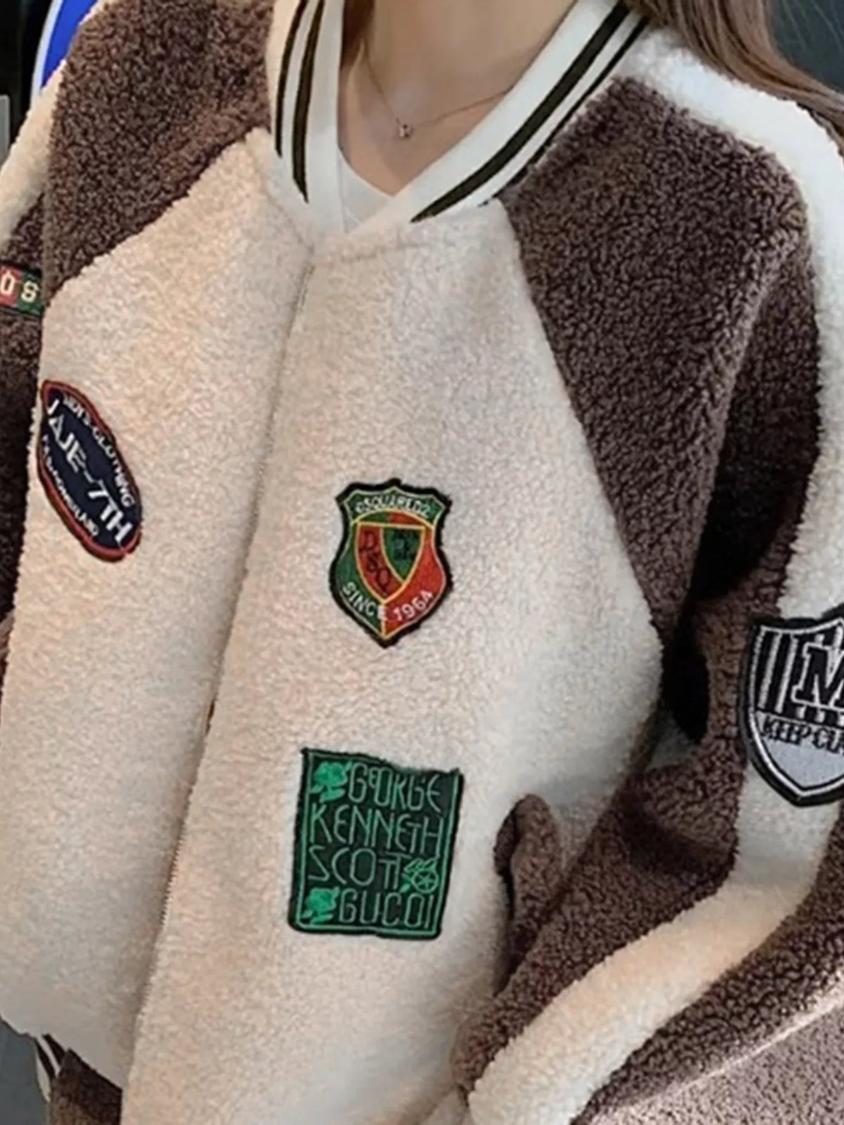 White fleece zip-up jacket with khaki raglan sleeves and embroidered shield patches
