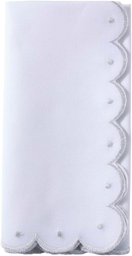 Close-up of white cloth napkin with scalloped edge embroidery and gold dot accents