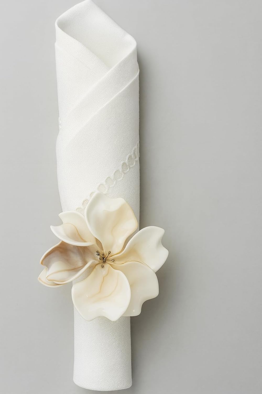 Single decorative napkin ring with cream flower on a white fabric-wrapped holder
