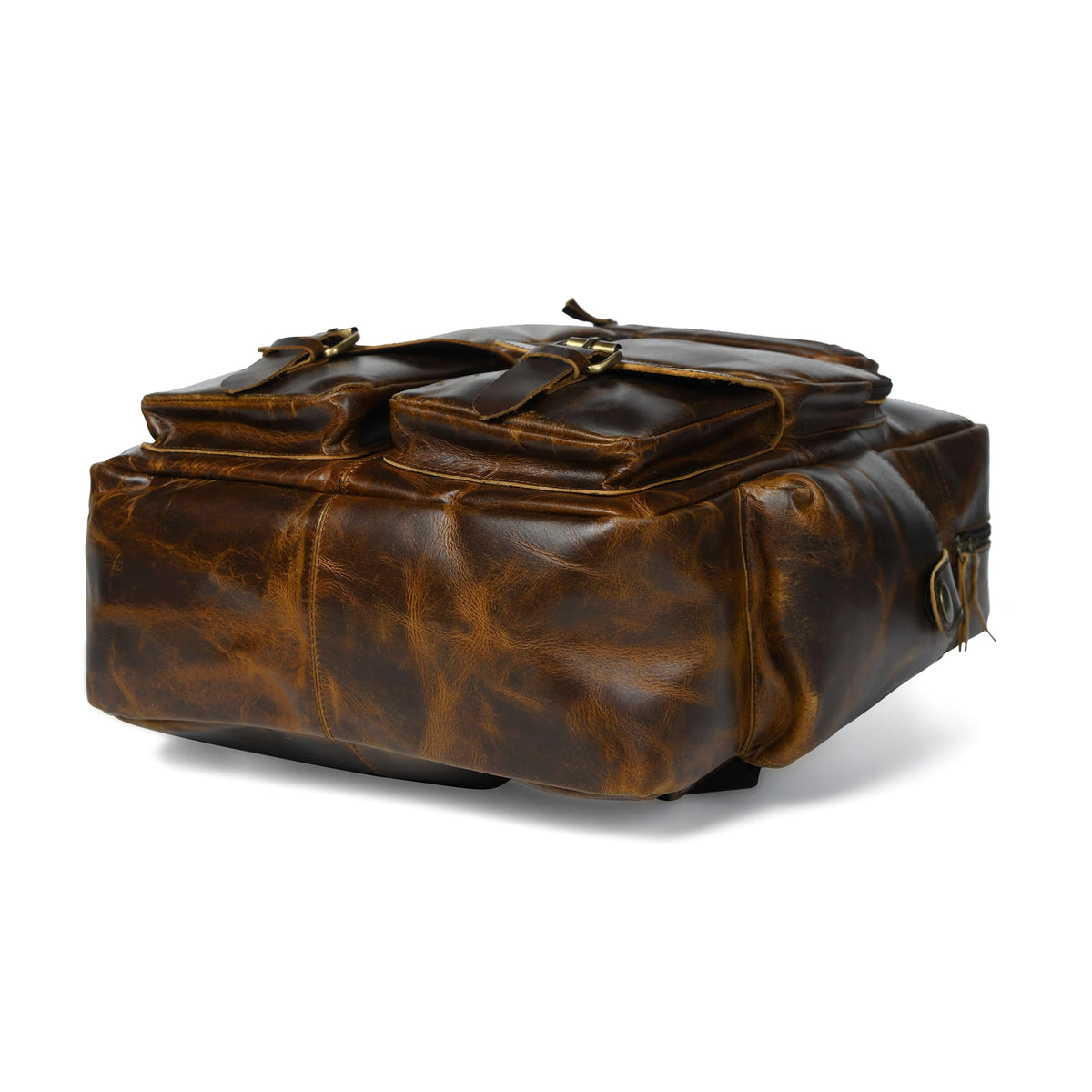 Brown leather backpack laid sideways with top handles, zippers, and side straps