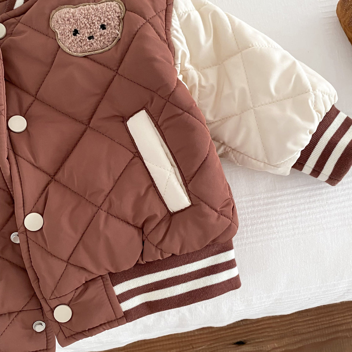 Kids reddish-brown quilted jacket sleeve panel with striped ribbed cuff and snap placket