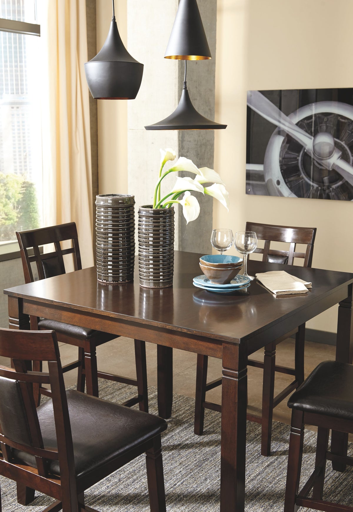 Brown counter table with four matching bar stools and dark cushioned seats