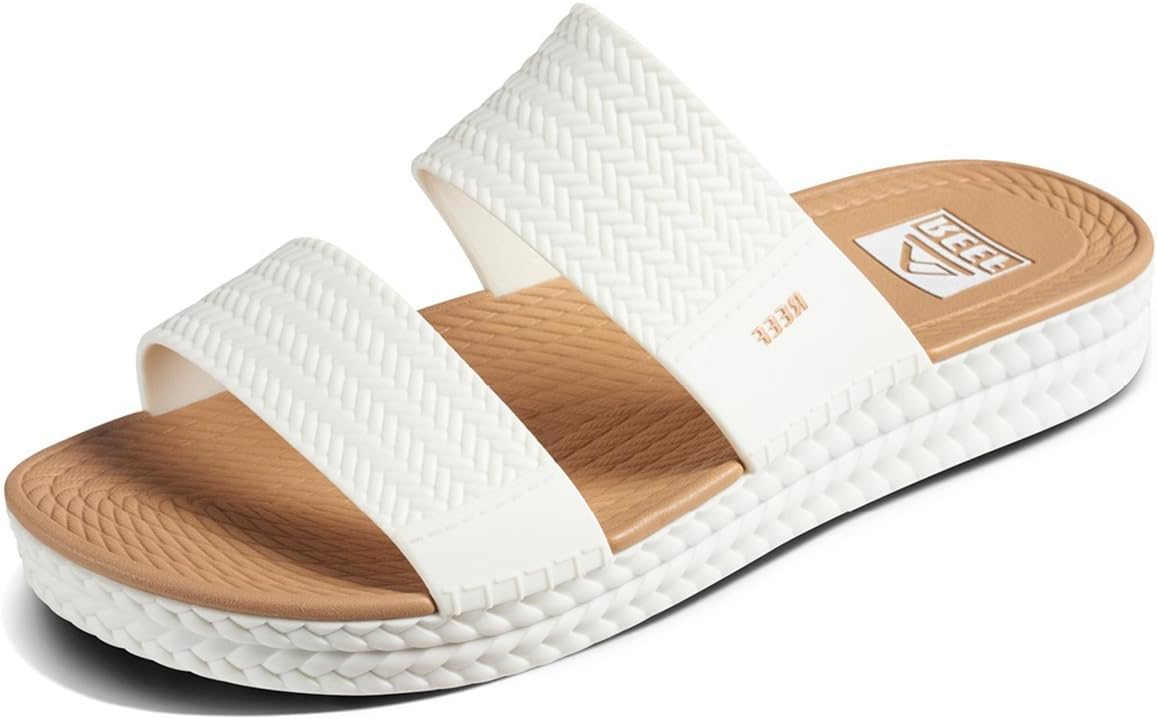 White platform slide sandals with tan footbed, wide strap, and REEF logo