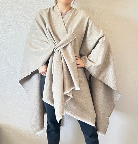 Beige women's fringe poncho shawl with tied front detail, worn with jeans