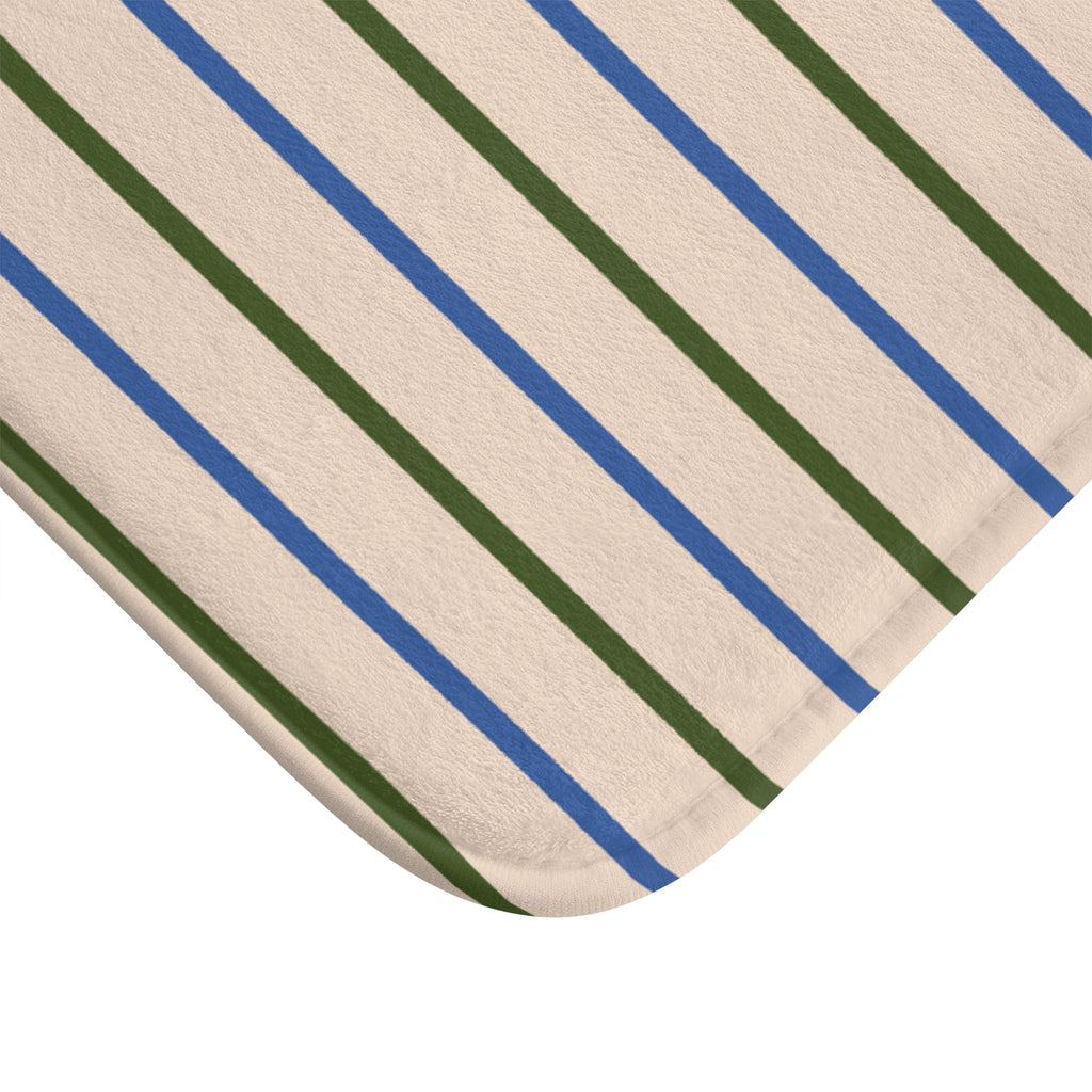 Close-up of striped bath mat corner with blue and green lines on beige fabric
