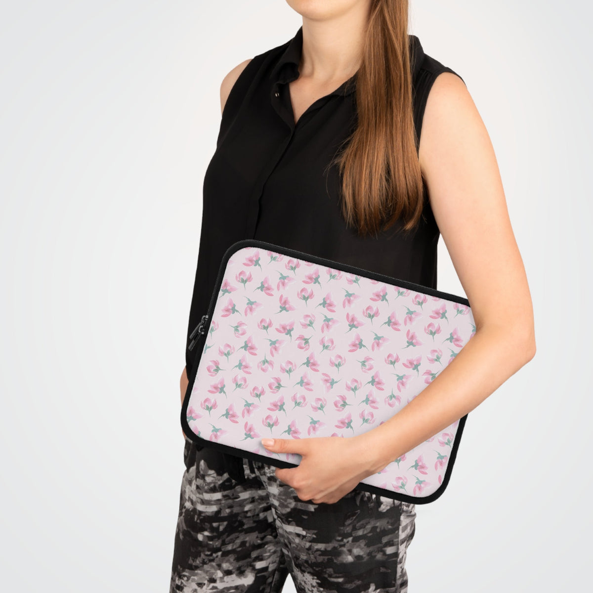 Floral laptop sleeve held in hands, pink-green flowers with black zipper trim