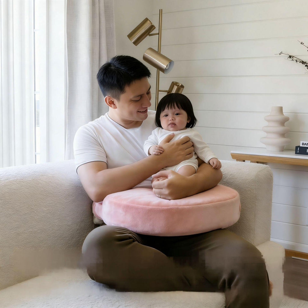 Pink wrap-around nursing pillow cradling a baby during feeding
