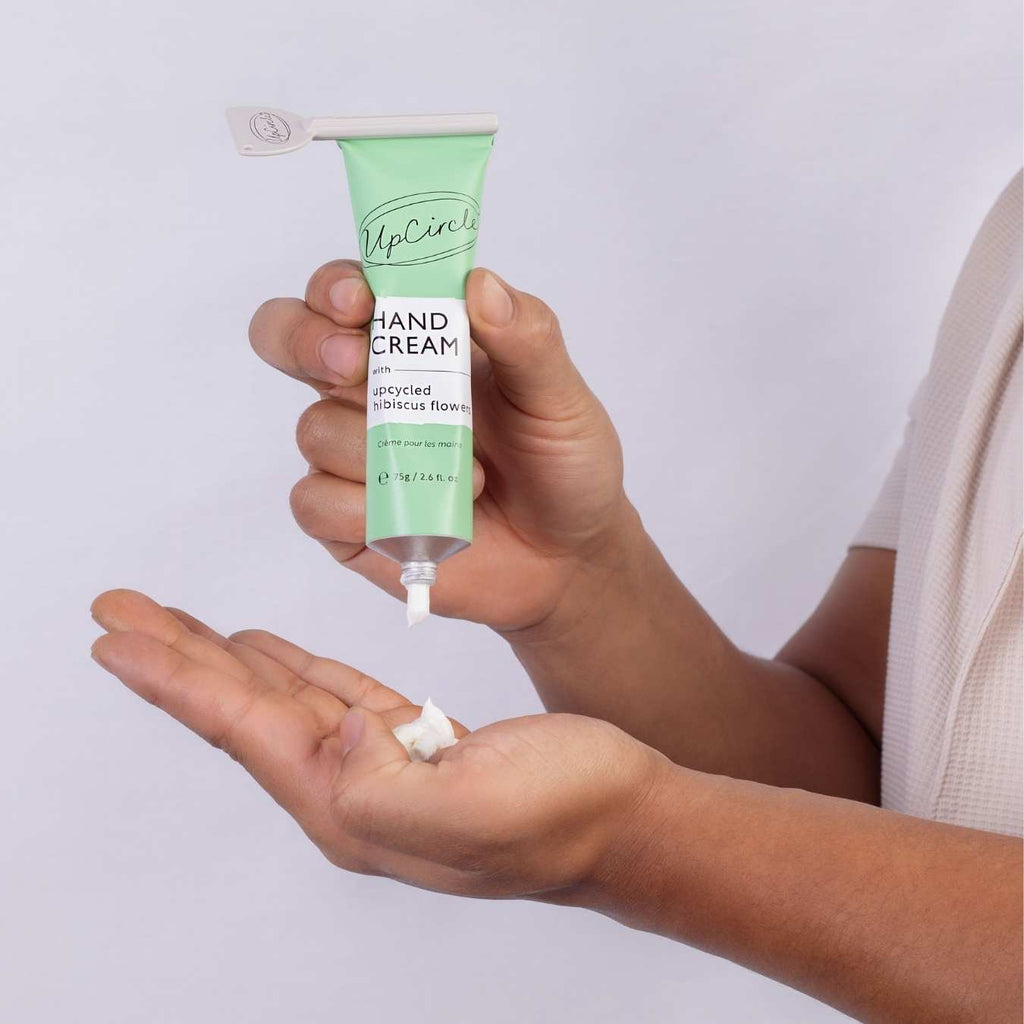 UpCircle green hand cream tube dispensing cream into open palm