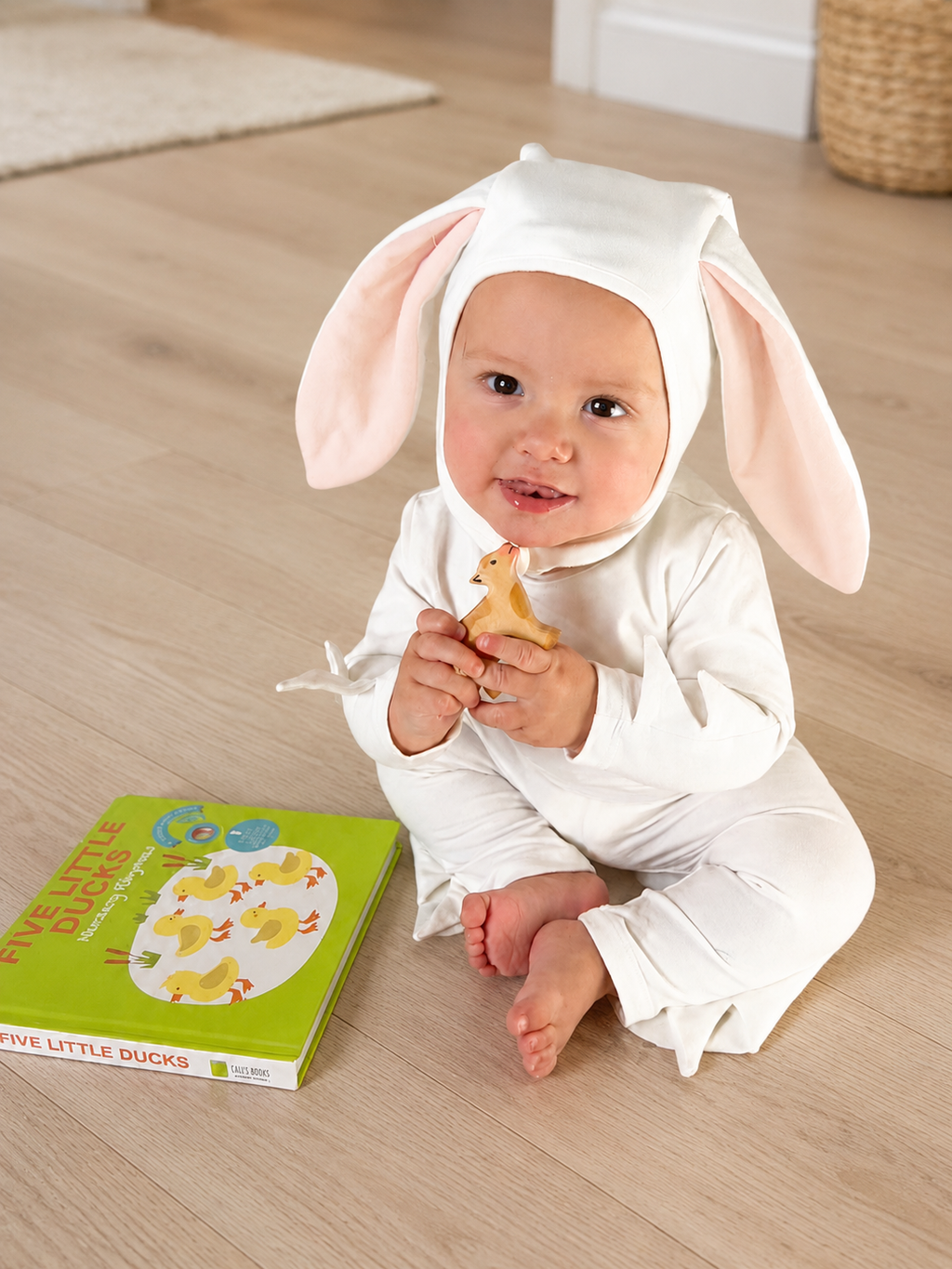 Baby ivory bunny hooded romper with long pink ears, holding a toy