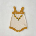 Cream knit baby coat with mustard straps and hem, floral wreath bib detail
