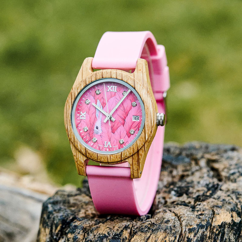 Pink wood wristwatch with roman numeral dial, white hands, and pink silicone strap.