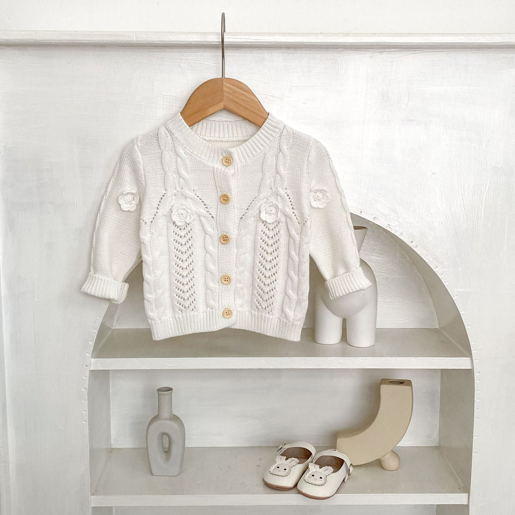 Cream knit baby jacket with standing collar, textured flower panels, button placket