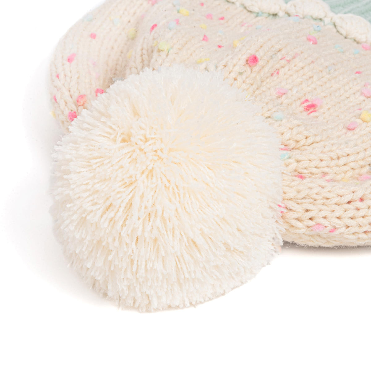 Cream knit beanie topper with pom-pom and pastel sprinkle flecks, close-up.