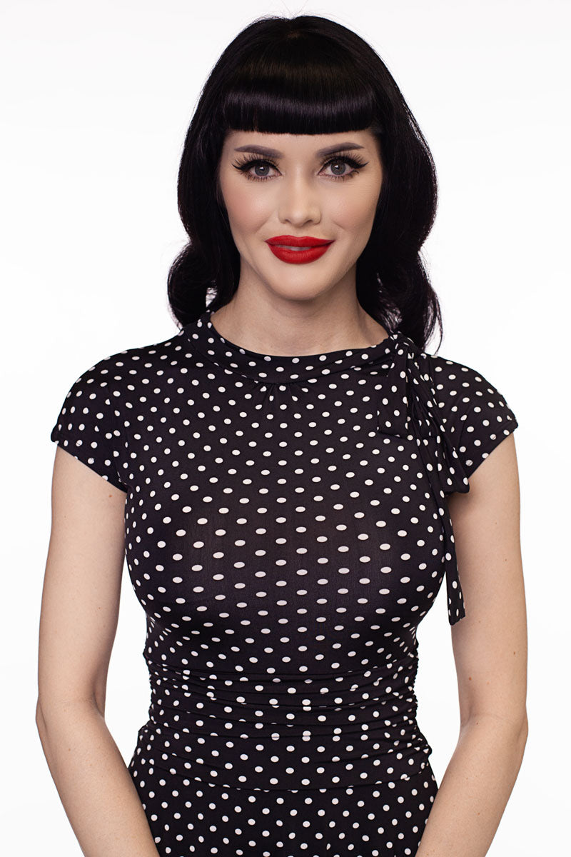 Close-up of black polka-dot dress with high neckline and draped cowl detail