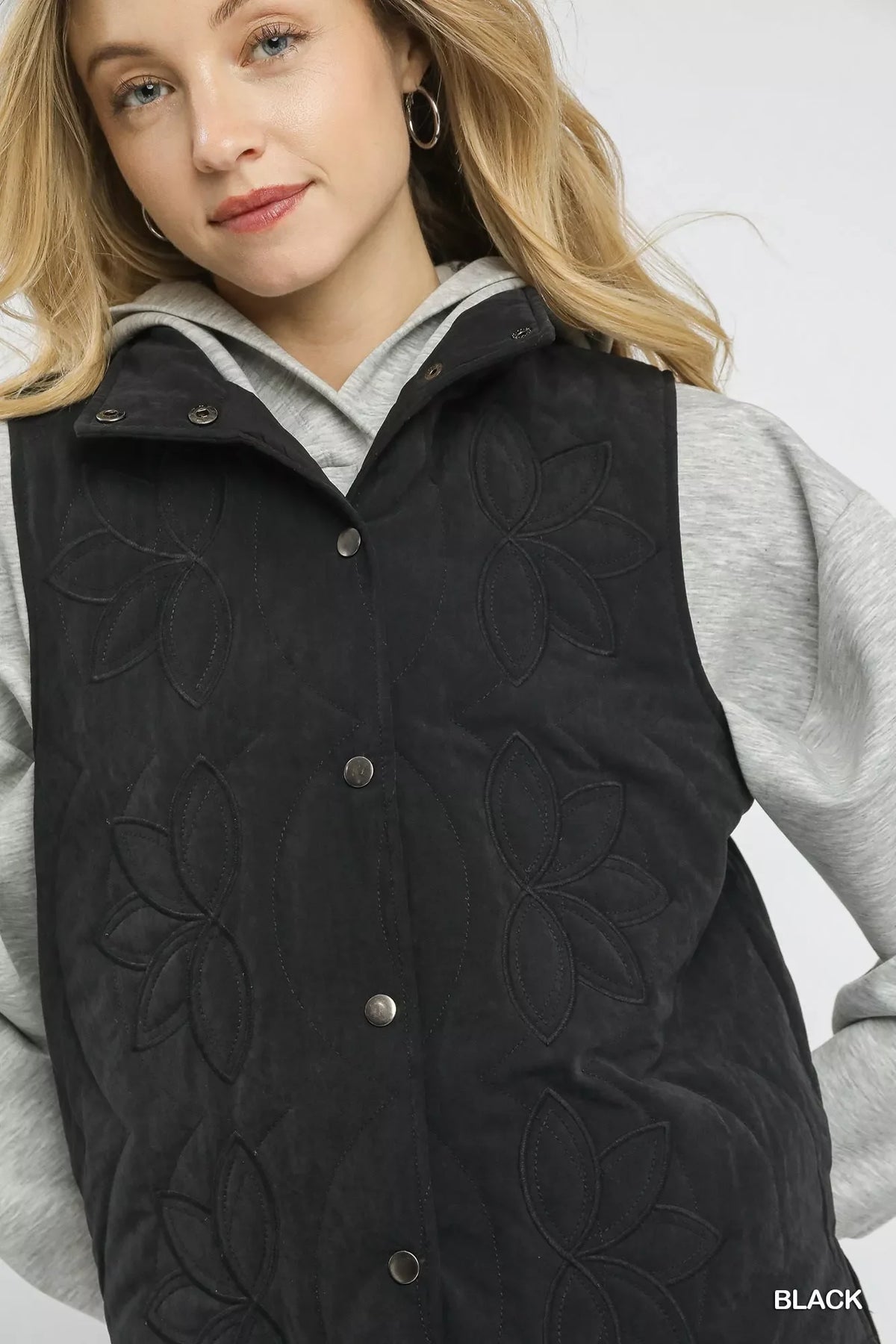 Close-up: black quilted embroidered vest with metal button front