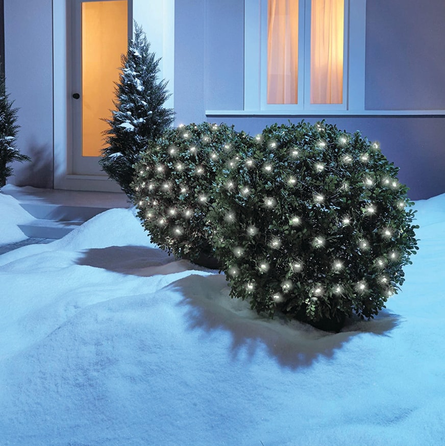 White LED net lights on dark green mesh, glowing across outdoor snow