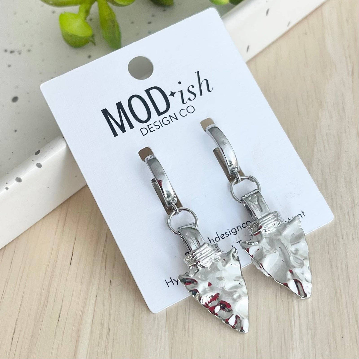 Silver-tone arrowhead huggie earrings with clear stones and red accents