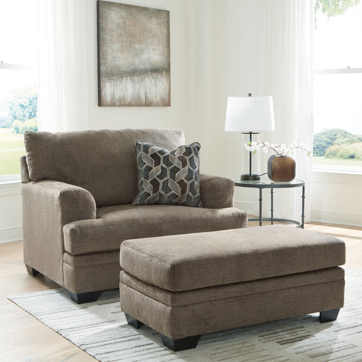 Light brown fabric armchair with square ottoman and geometric pattern throw pillows